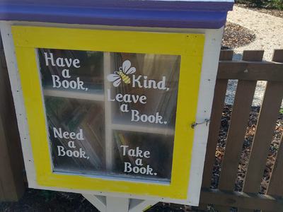 Little book library in the children's garden decorated with painted bees.