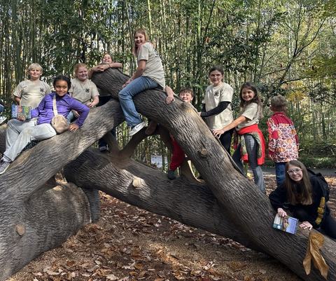 Group of 4H children sitting on tree log at zoo.