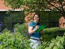 A Durham community member counts pollinators and records the number counted in a verdant demonstration garden for the 2025 Great Southeast Pollinator Census .
