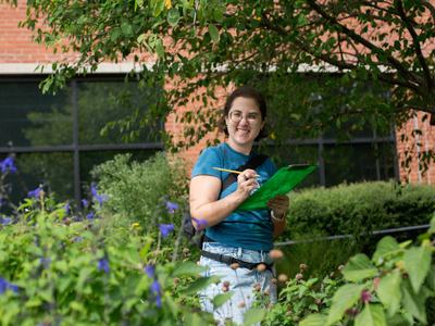 A Durham community member counts pollinators and records the number counted in a verdant demonstration garden for the 2025 Great Southeast Pollinator Census .