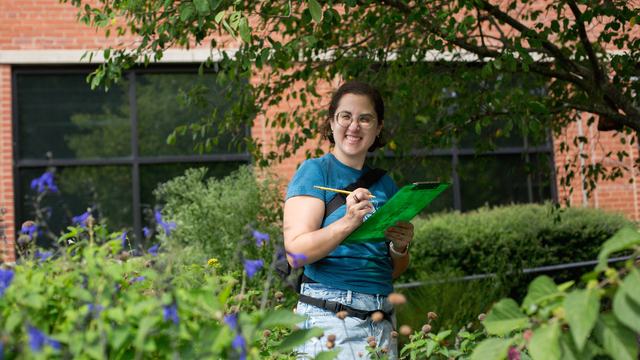 A Durham community member counts pollinators and records the number counted in a verdant demonstration garden for the 2025 Great Southeast Pollinator Census .