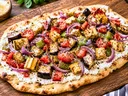Rustic flatbread spread with creamy ricotta and topped with roasted Italian eggplant, squash, tomatoes, green bell peppers, and red onion, seasoned with herbs and served on a wooden board.