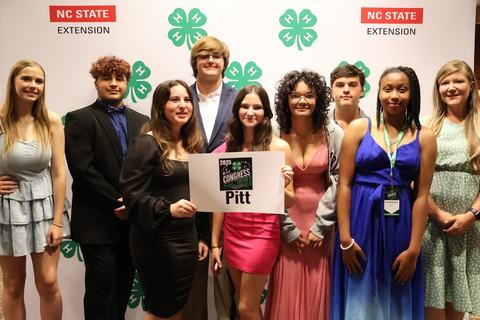 Group of well-dressed youth posing with a Pitt County 2025 NC 4-H Congress sign.