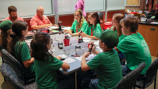 youth teams sitting at table with buzzers in hand, waiting to answer questions
