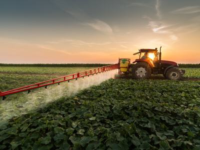 Tractor spraying pesticides on vegetable field with sprayer at spring