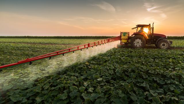 Tractor spraying pesticides on vegetable field with sprayer at spring