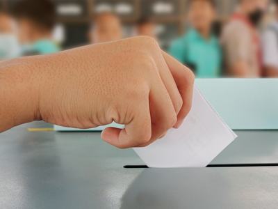 Childs hand putting ballot in box.