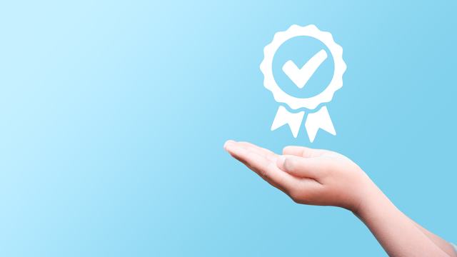 Hand supporting a checkmark symbolizing meeting a requirement.