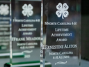 Close-up of three engraved North Carolina 4‑H Lifetime Achievement glass awards lined up at the annual NC 4-H Adult and Alumni Awards.
