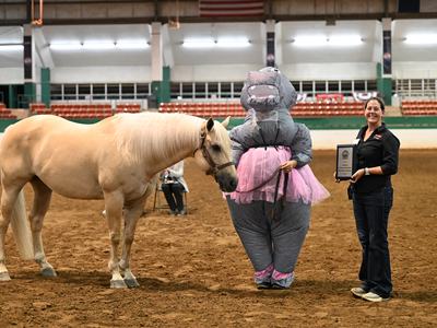 Alumni Showmanship Sponsorship Challenge winner, Samantha Taylor, posing with her palomino horse and Alaina Cross. Samantha is where a hippopotamus costume.