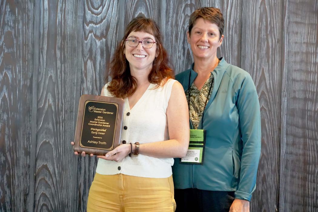 Durham County Horticulture Agent Ashley Troth stands with statewide EMG program manager Charlotte Glen while holding the 2026 Distinguished Early Career Award