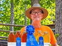 local beekeeper with awards and beehive with mountains in the background