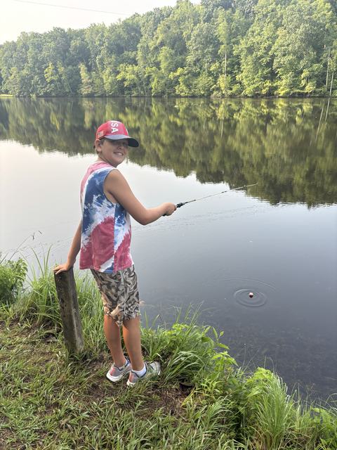 4-H camper fishing in pond at camp.