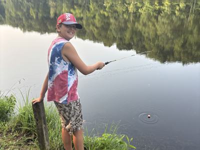 4-H camper fishing in pond at camp.