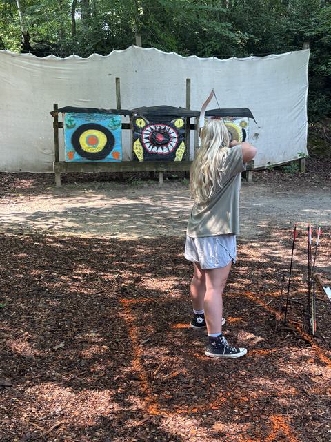 4-H camper shooting an arrow at camp.