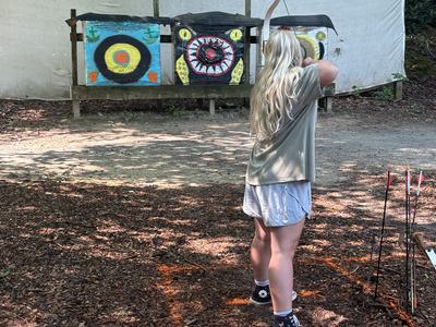 4-H camper shooting an arrow at camp.