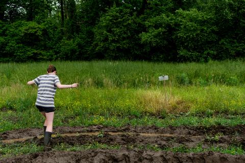 Person walking through mud to reach stink bug trap in field