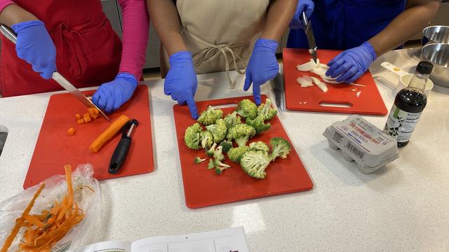 Students chopping vegetables on a cutting board