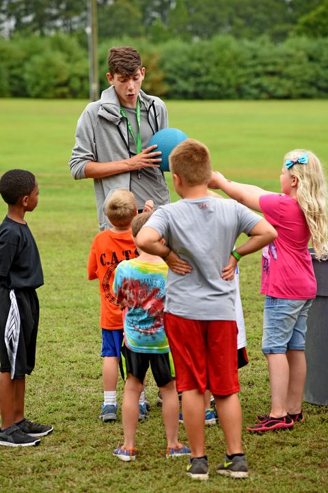 4-H camp counselor explains an outdoor game to campers