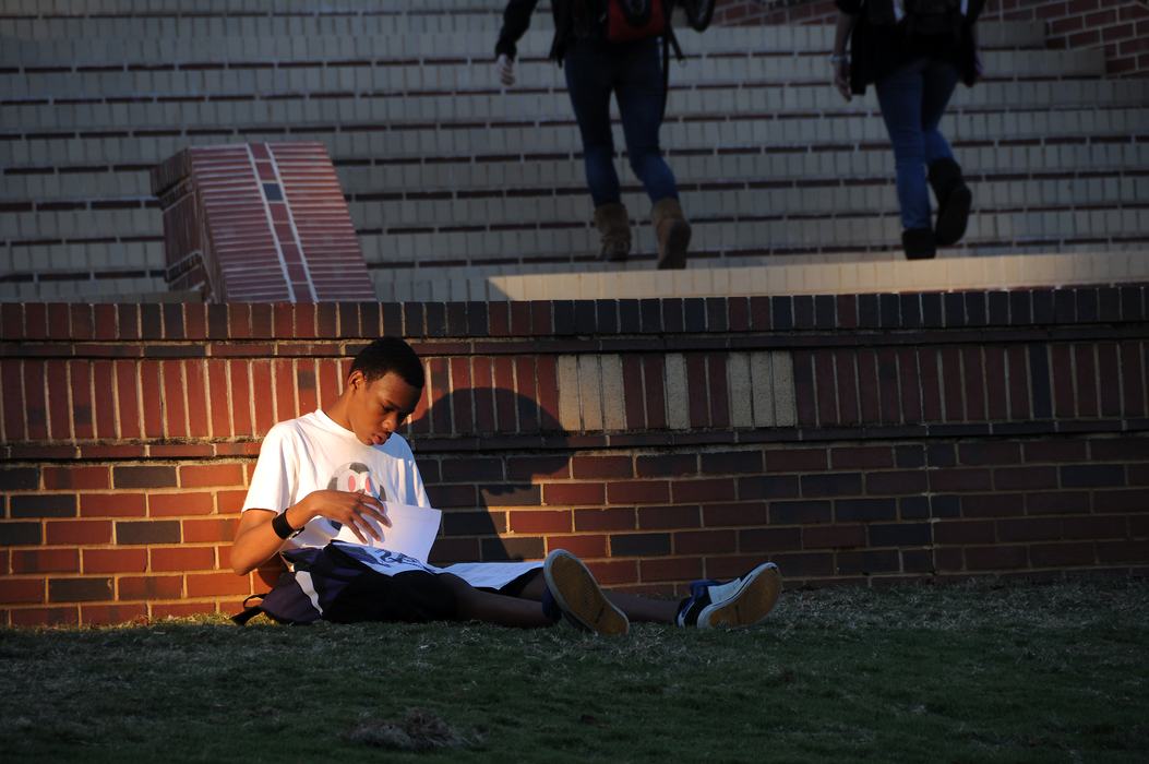 A person studies next to a brick wall.