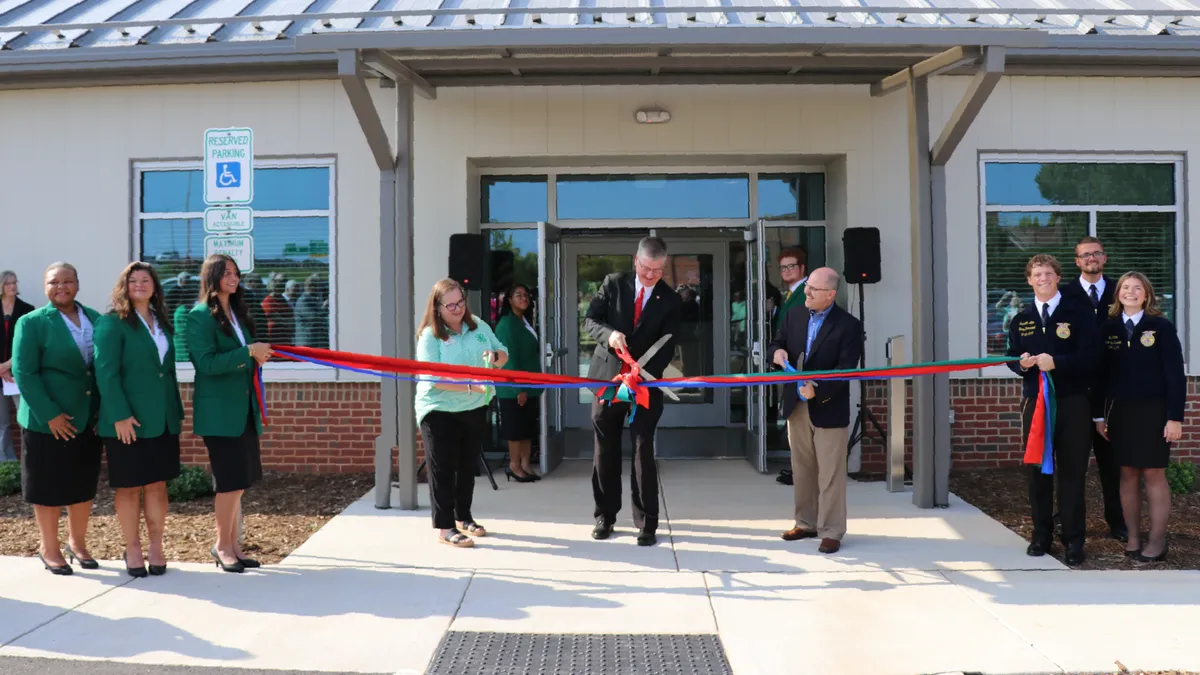 University, Extension, 4-H and FFA representatives cut red, blue and green ribbons outside the entrance of the new CALS Extension Building as North Carolina 4-H and FFA state officers hold them.
