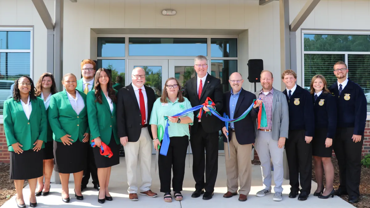 North Carolina 4-H and FFA state officers join university and Extension representatives outside the CALS Extension Building following the ribbon cutting, holding sections of the red, blue and green ribbon.