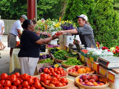 Farmers selling produce to a customer.