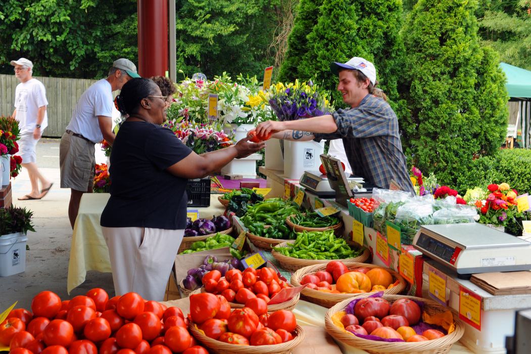Farmers selling produce to a customer at Carrboro Farmers' Market.