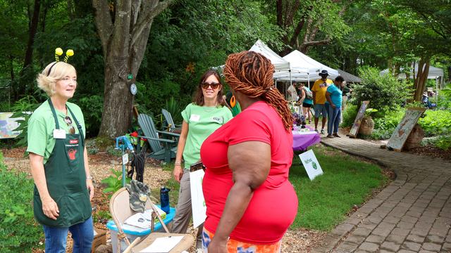 a woman talking to two women at an event in a garden