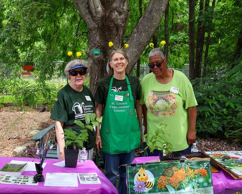 three Master Gardener volunteers standing at an education display table