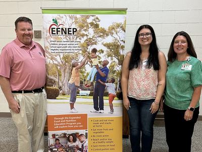 Kayley with partners standing in front of EFNEP banner
