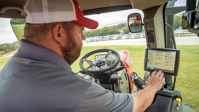 A farmer in a tractor cab using a computer screen
