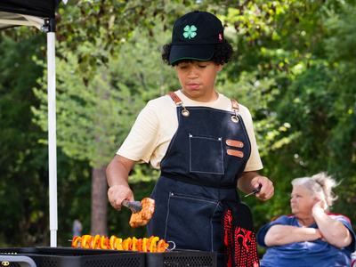 4-H member grills food during the Outdoor Cookery competition at Southeast District Activity Day.