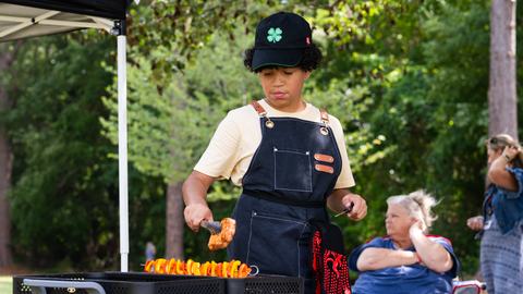 4-H member grills food during the Outdoor Cookery competition at Southeast District Activity Day.