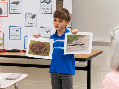 Cloverbud 4-H member gives a presentation about the science of snakes while displaying printed photographs for judges during South Central District Activity Day.