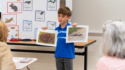 Cloverbud 4-H member gives a presentation about the science of snakes while displaying printed photographs for judges during South Central District Activity Day.