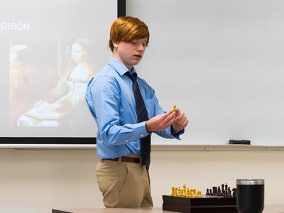 4-H member explains a chess concept while using a chessboard as a visual aid during West District Activity Day.
