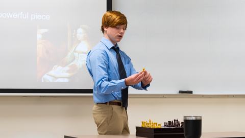 4-H member explains a chess concept while using a chessboard as a visual aid during West District Activity Day.