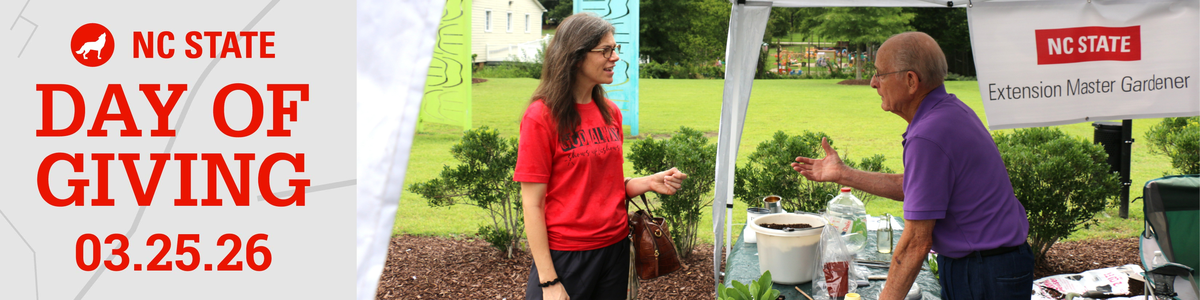A Master Gardener volunteer staffing an information tent shares gardening advice with a community member.