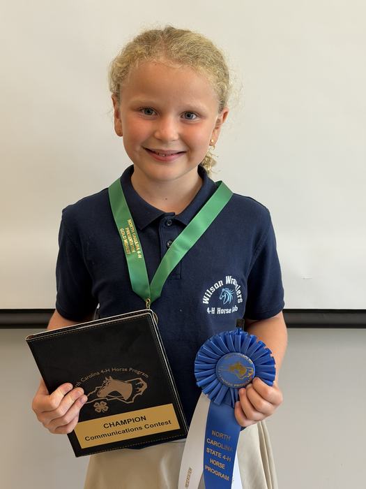 The 8-10 year old presentation winner, Delilah Baker, with her ribbon, medal and padfolio prizes.