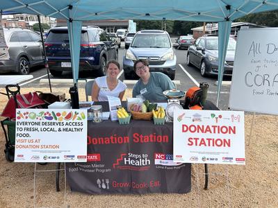 Extension employees sit at the first Donation Station table at the Pittsboro Farmers Market.