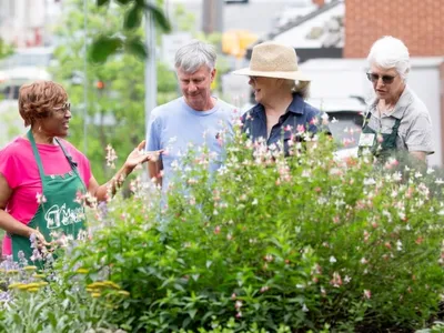 Master Gardener volunteers surrounded by blooming plants engage with community members during a tour of the demonstration garden at the Extension center in Durham County.