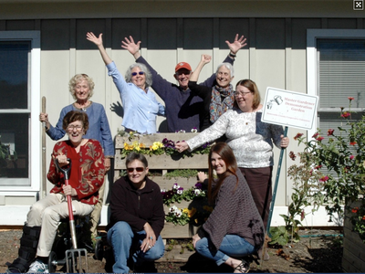 7 volunteers with raised hands holding a welcome sign