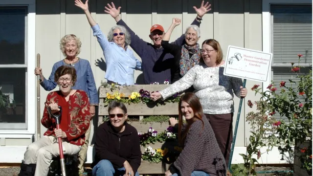 7 volunteers with raised hands holding a welcome sign
