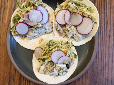 Plate with fish tacos topped with slaw and radishes.