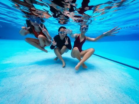 A group of children are swimming underwater in a pool.