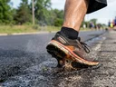 A running shoe has a rubber sole melting on the hot concrete