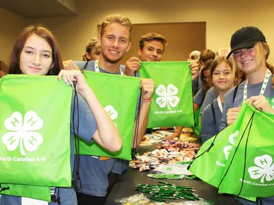 4-H members hold green drawstring bags while assembling care packages during a hands to service project at 4-H Congress.