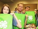 4-H members hold green drawstring bags while assembling care packages during a hands to service project at 4-H Congress.