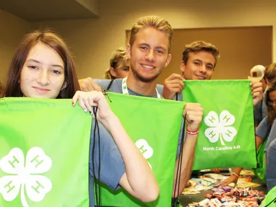 4-H members hold green drawstring bags while assembling care packages during a hands to service project at 4-H Congress.